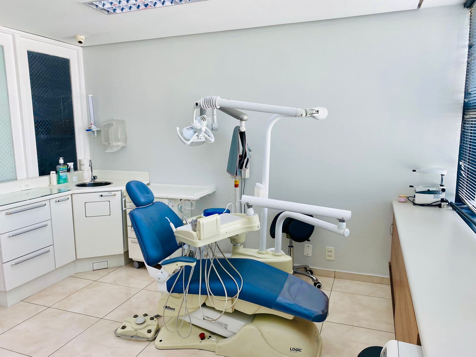Consultório da Alô Dente com cadeira azul e janela com persiana
